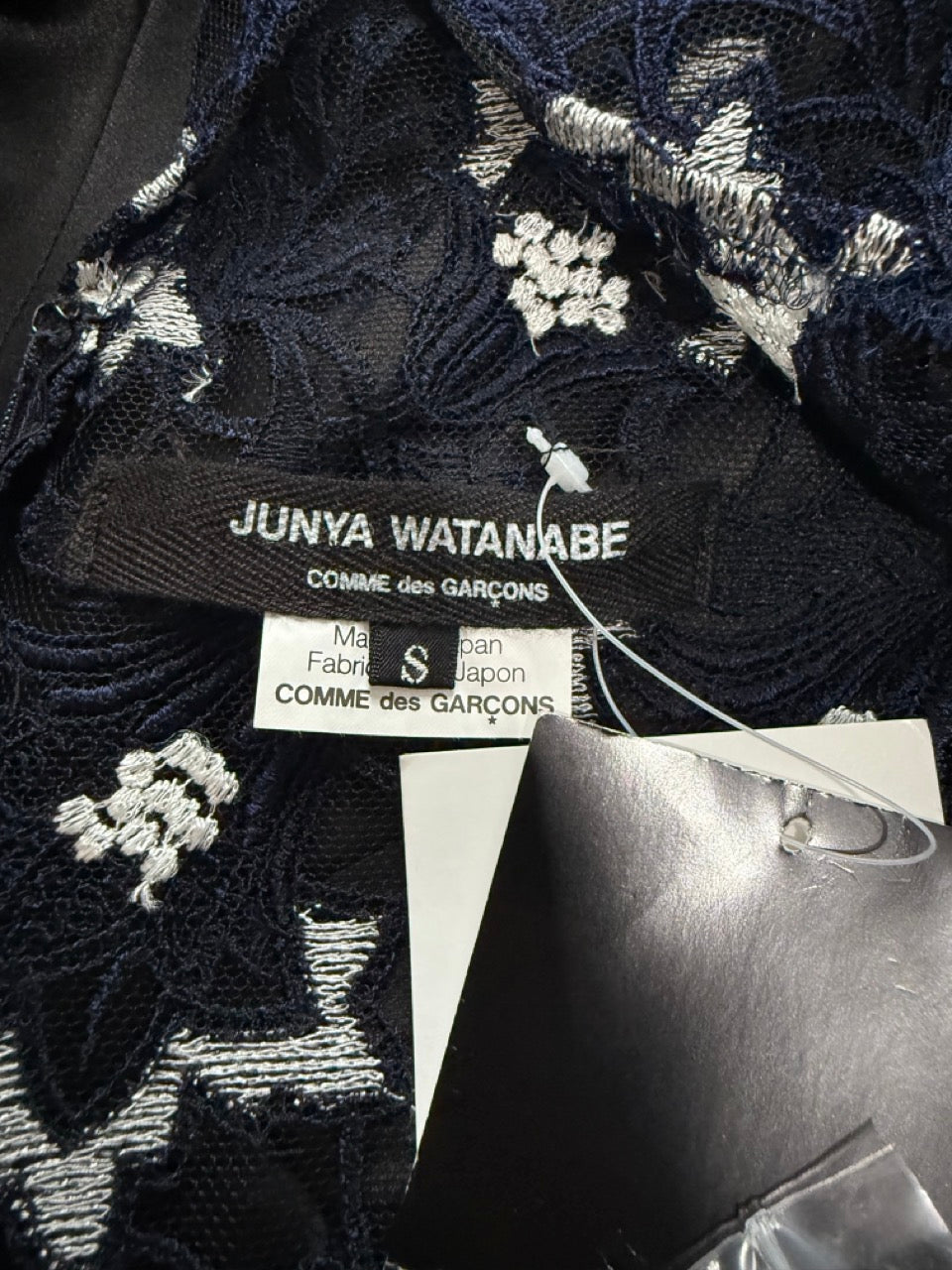 Black embroidered fabric with Junya Watanabe and Comme des Garçons labels.