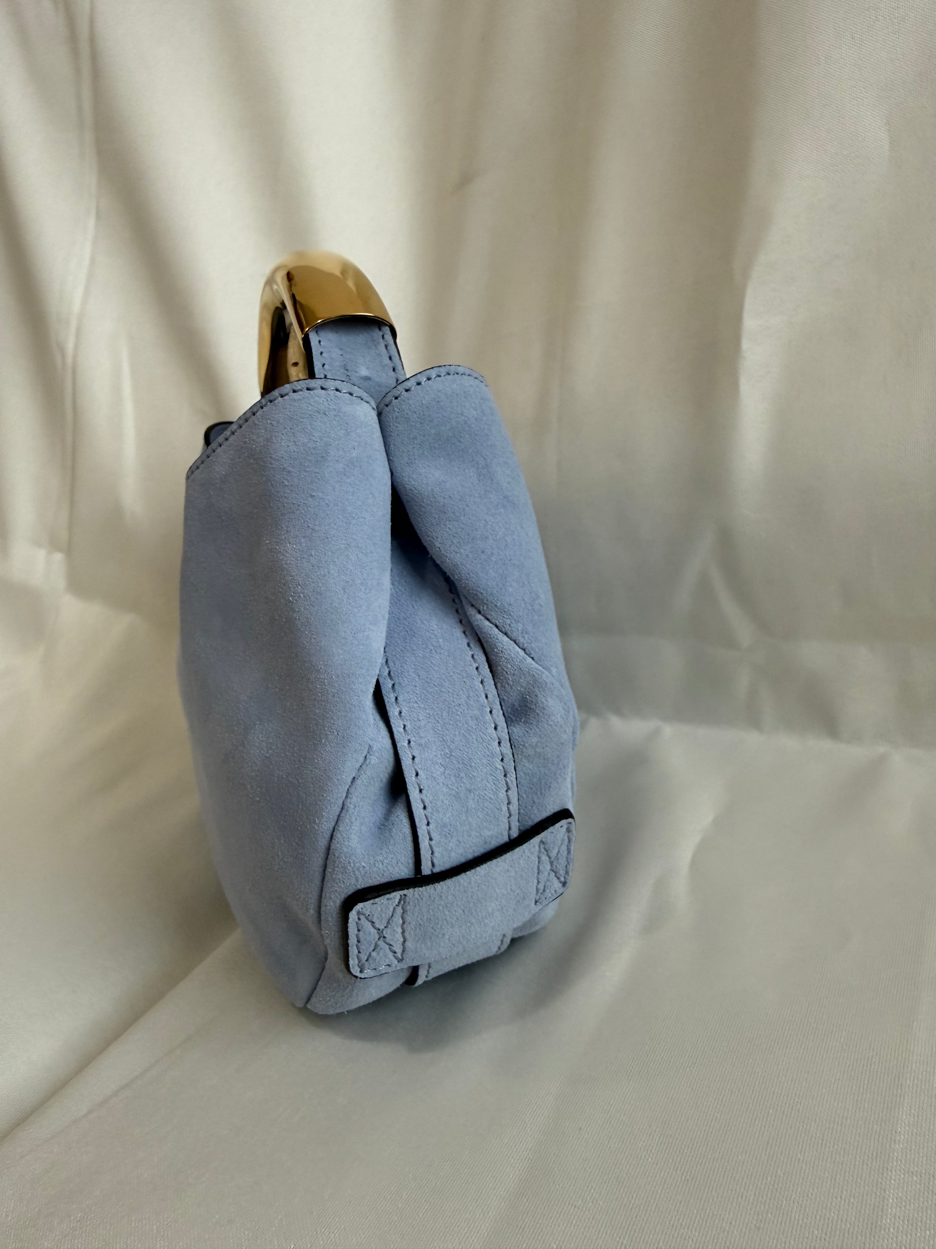 Blue fabric bag with a gold zipper on a beige background